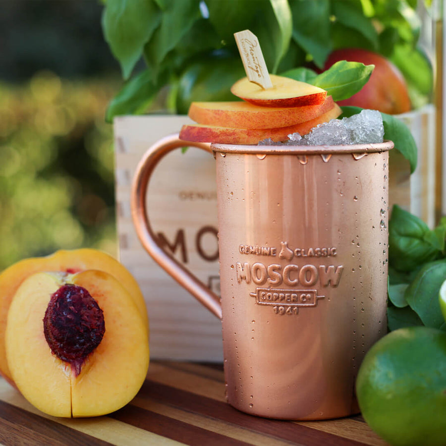 Fresh peaches liven up the typical Moscow Mule, served in a 100% pure copper mug.